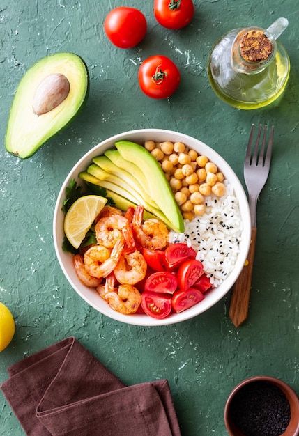 Un bol de riz, de crevettes, d'avocat, de tomates, de pois chiches et de citron vert Une alimentation saine