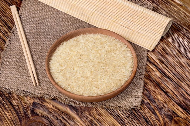 Bol de riz cru avec baguettes et natte de bambou