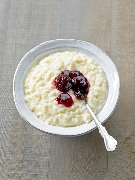 Bol de riz sain et pudding au lait décoré de confiture sur une table de cuisine en bois