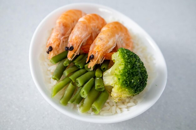 Un bol de riz trois crevettes roi haricots verts et brocoli est sur la table concept de cuisine asiatique