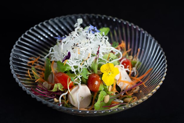 Un bol de salade avec une fleur colorée sur le dessus.