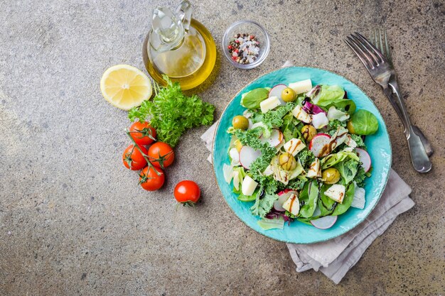 Bol de salade fraîche et saine avec des légumes et des verts sur fond gris