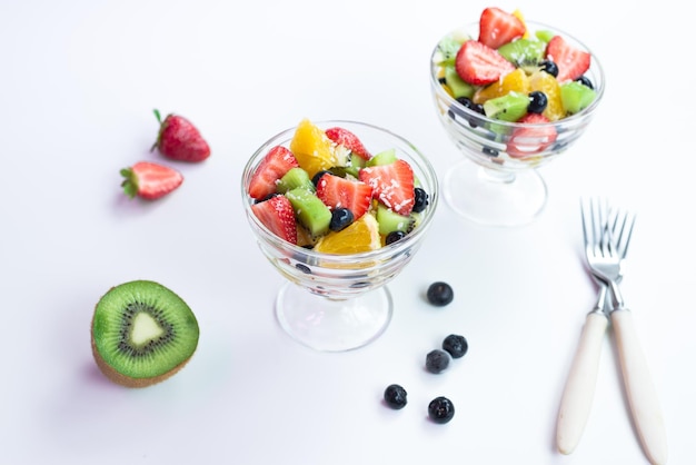 Un bol de salade de fruits avec une cuillère à côté