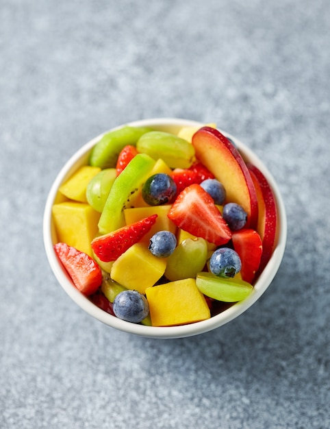 Bol de salade de fruits frais colorés sur table de cuisine, vue de dessus