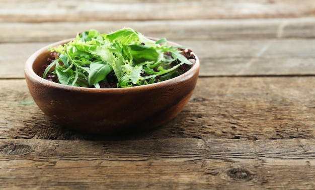 Bol de salade verte mélangée sur fond de bois