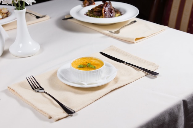 Bol de savoureuse soupe à la citrouille d'automne servie à une table avec un assortiment d'autres apéritifs dans un restaurant