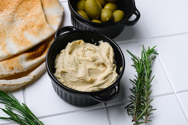 Bol de savoureux houmous frais sur fond de table en carreaux de céramique blanche