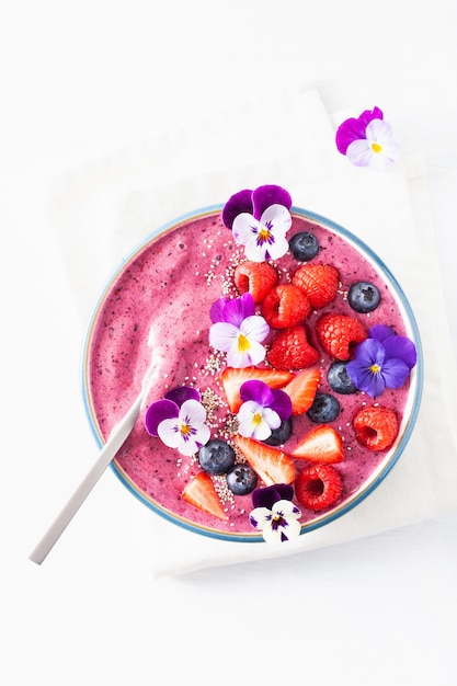 Bol de smoothie aux baies d'été sain avec des fleurs et des graines de chia