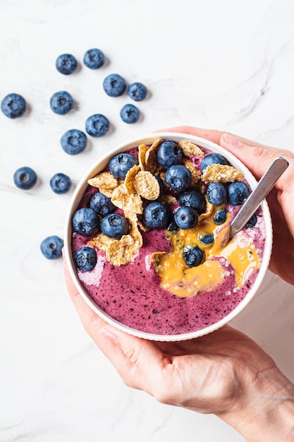 Bol de smoothie aux bleuets avec céréales au beurre d'arachide et fond de marbre blanc de baies fraîches