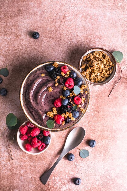 Bol de smoothie aux bleuets avec granola banane et graines de chia alimentation saine régime végétalien ou végétarien concept alimentaire fond clair