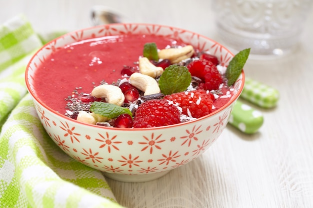 Bol de smoothie aux framboises, ananas et banane et garniture de baies et de graines