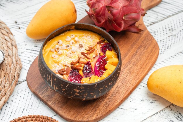 Bol de smoothie aux fruits à la mangue dans une tasse de coquille de noix de coco