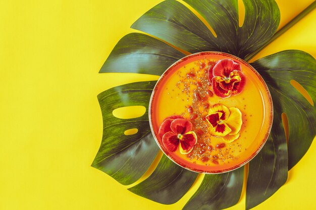 Bol à smoothie avec fleurs de pansy comestibles, graines de chia et baies de goji