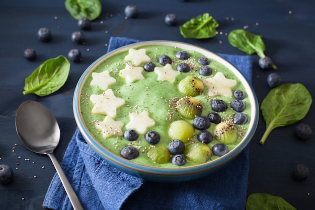 Bol de smoothie sain aux épinards verts avec myrtille, étoiles de pomme, kiwi, graines de chia