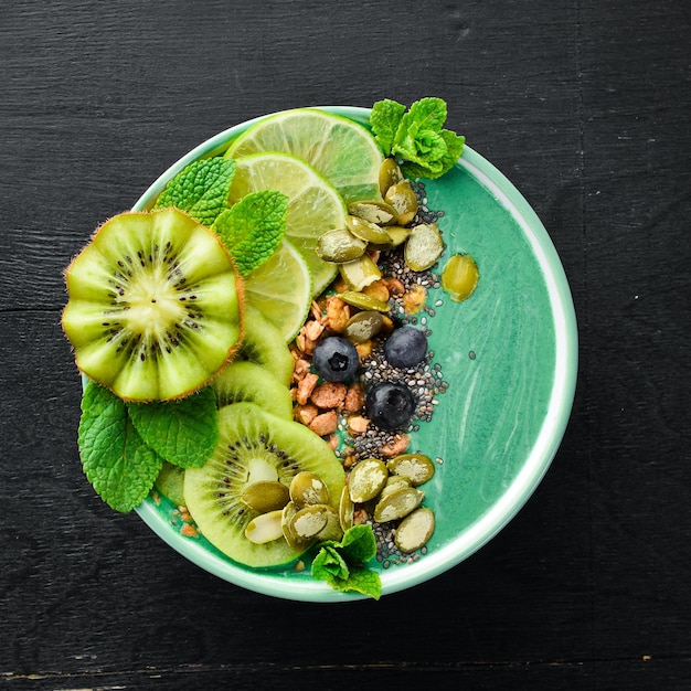 Bol de smoothie avec spiruline verte kiwi menthe et graines de citrouille Petit-déjeuner Vue de dessus Espace libre pour votre texte