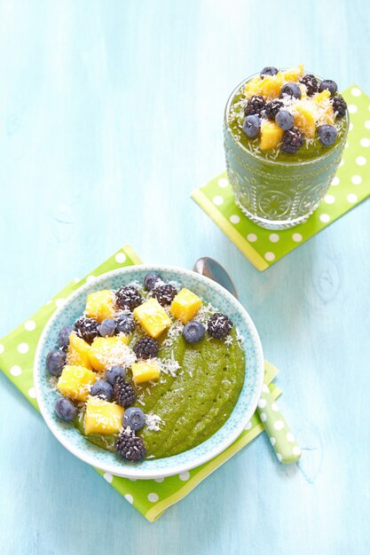 Bol de smoothie vert petit déjeuner garni de fruits