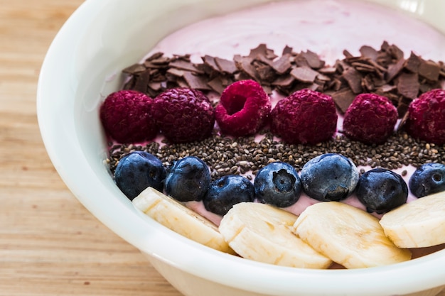 Un bol à smoothies avec des baies fraîches, des bananes, des graines de chia et du chocolat pour une alimentation saine