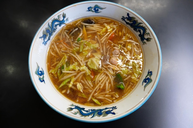 Un bol de soupe asiatique avec un bord bleu et un motif bleu sur le fond.