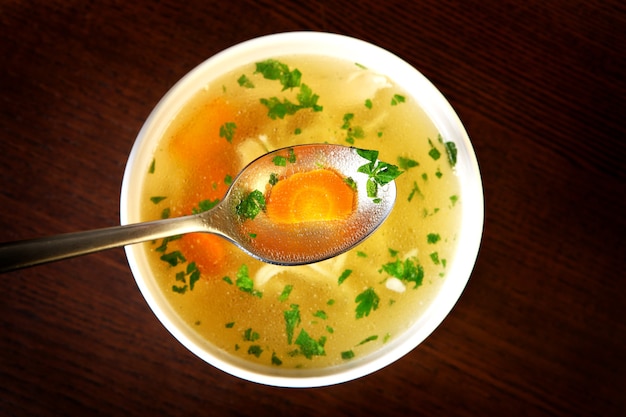 un bol de soupe au poulet traditionnelle servi dans un bol sur bois