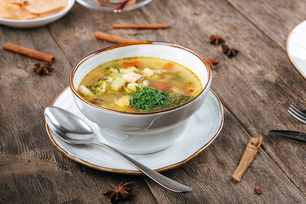 Bol de soupe aux légumes avec du poulet sur la table en bois