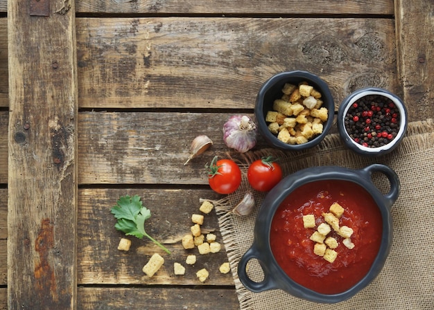 Bol de soupe aux tomates avec des craquelins et des clous de girofle sur une table en bois rustique