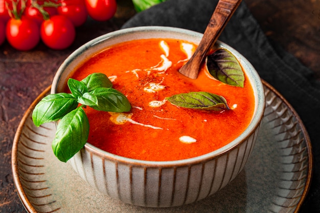 un bol de soupe aux tomates traditionnelle d'espagne avec de la crème et du basilic sur la table close up tomate et basilic