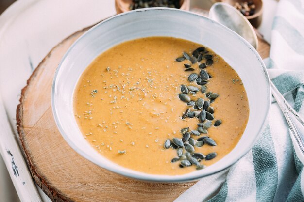 Un bol avec une soupe de citrouille décorée de graines de citrouille