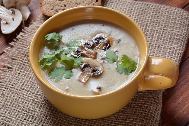 Un bol de soupe à la crème aux champignons avec des champignons frits et du persil frais.
