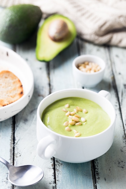 Bol de soupe à la crème de brocoli et pois verts dans un bol blanc avec avocat