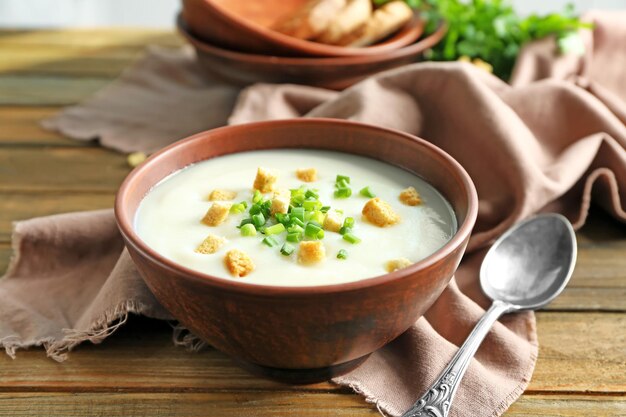 Bol avec soupe à la crème de pommes de terre sur table