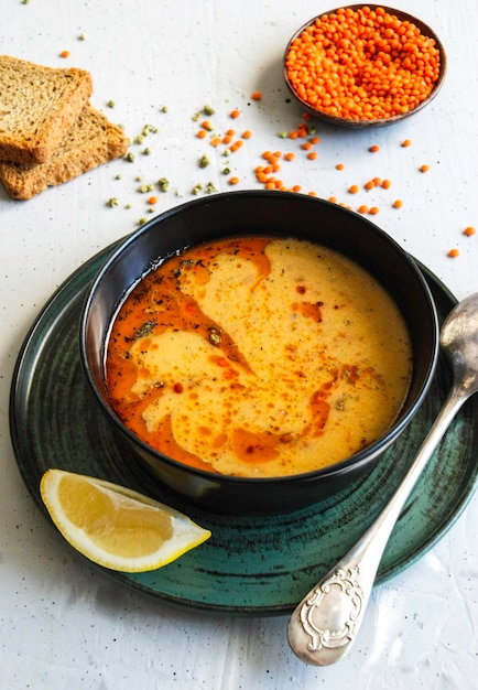 Un bol de soupe jaune avec une cuillère sur une assiette