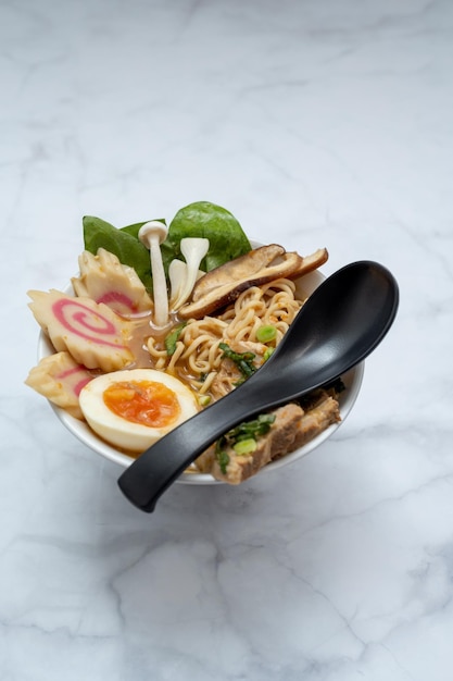 Bol à soupe ramen avec cuillère noire sur table en marbre