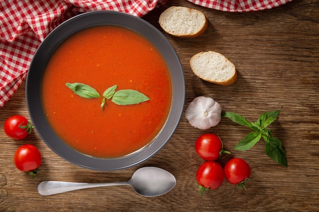 Bol de soupe de tomate au basilic sur table en bois