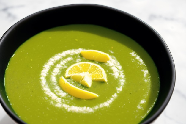 Un bol de soupe verte avec des tranches de citron sur le dessus