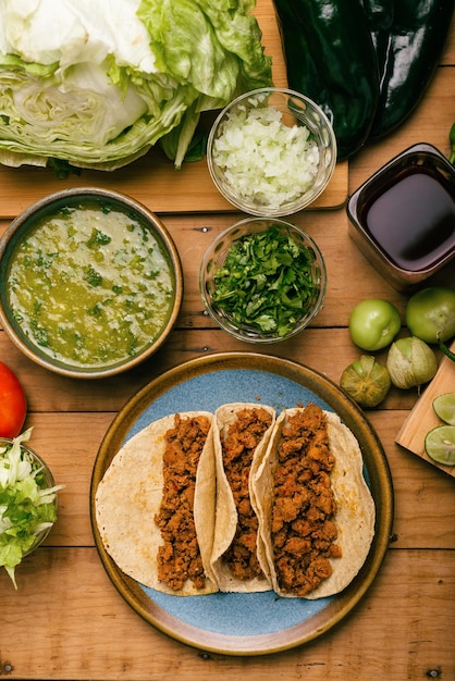 Bol de tacos au boeuf mariné avec salsa verde et légumes sur une table en bois Tacos de adobada