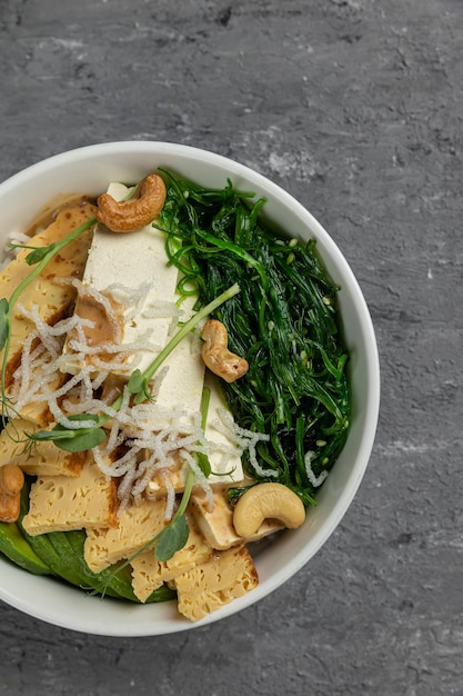 Un bol de tofu avec des verts et des noix