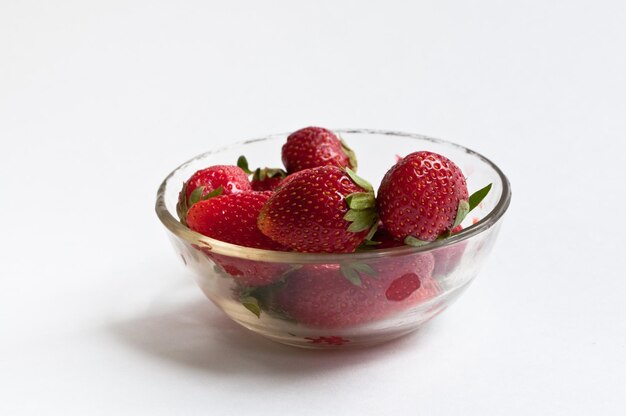 Bol transparent rempli de fraises sur fond blanc