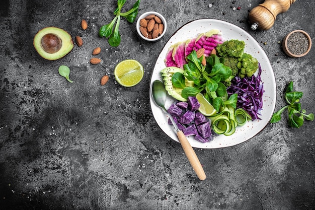 Bol végétarien sain salade végétalienne avec patates douces brocoli avocat chou violet concombre pastèque radis et amandes Alimentation saine régime alimentaire concept vue de dessus