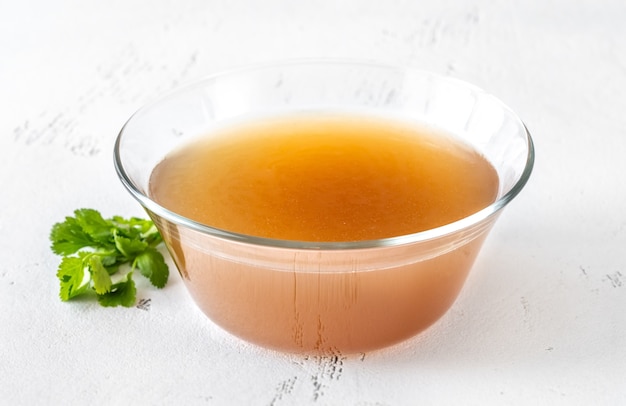 Bol en verre de bouillon d'os de boeuf sur table blanche