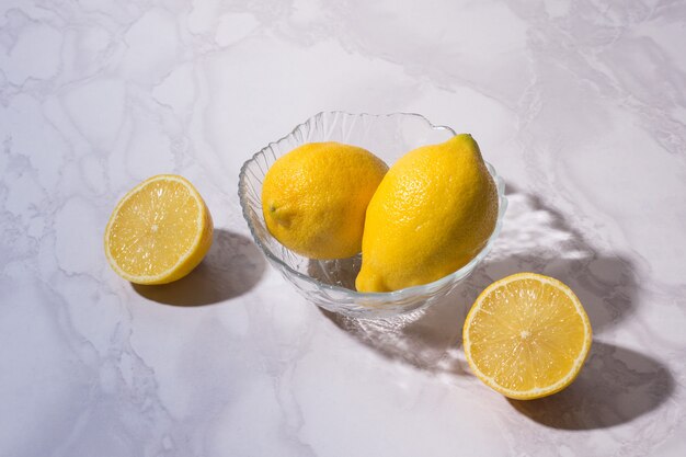 Bol en verre avec des citrons sur blanc