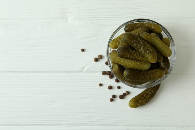 Bol en verre avec concombres marinés sur table en bois blanc