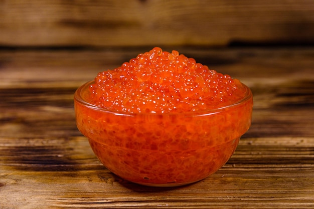 Bol en verre avec du caviar rouge sur une table en bois