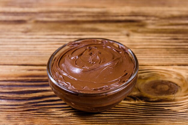 Bol en verre avec du chocolat à tartiner sur une table en bois