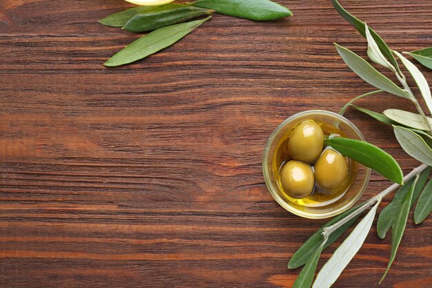 Bol en verre avec de l'huile d'olive sur une table en bois