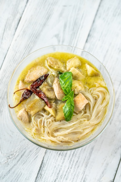 Bol en verre de nouilles au curry vert décoré de basilic frais