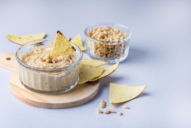 Bol en verre de trempette de pois chiches houmous et huile d'olive avec pain pita ou frites sur un plateau en bois