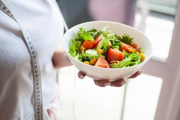 Bol vert salade écologique savoureuse saine dans la main femme sur cuisine légère