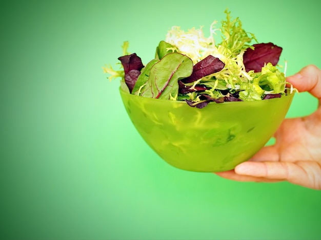bol vert avec salade mixte dans la main de la femme