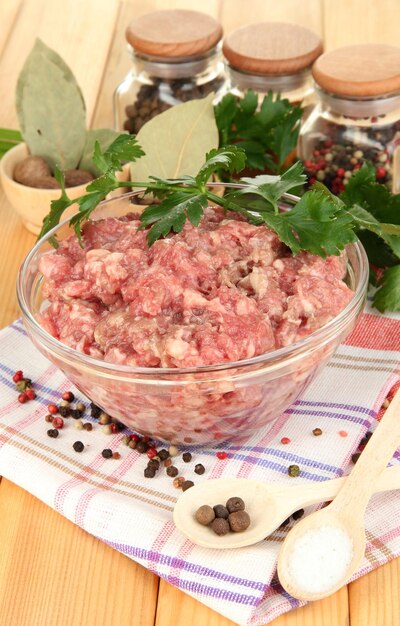 Bol de viande hachée crue aux épices sur table en bois