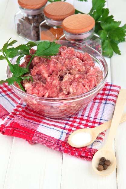 Un bol de viande hachée crue avec des épices sur une table en bois